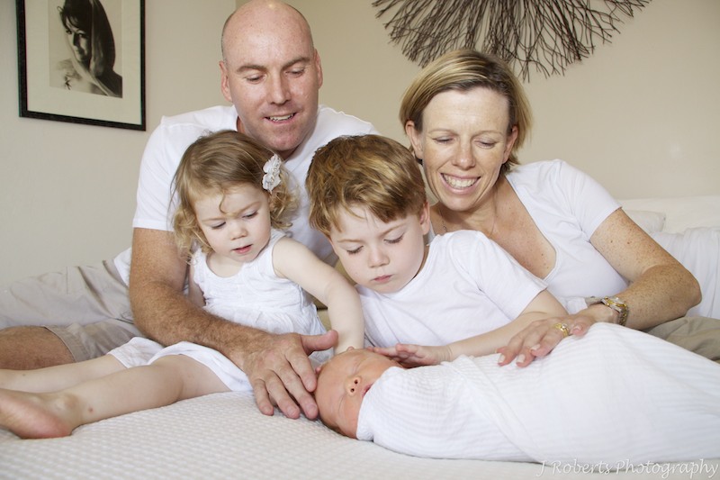 Family patting baby - newborn portrait photography